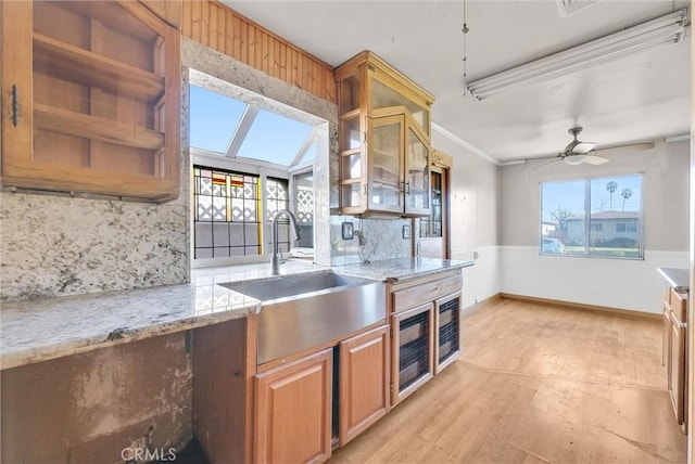 kitchen with crown molding, light stone countertops, ceiling fan, sink, and tasteful backsplash