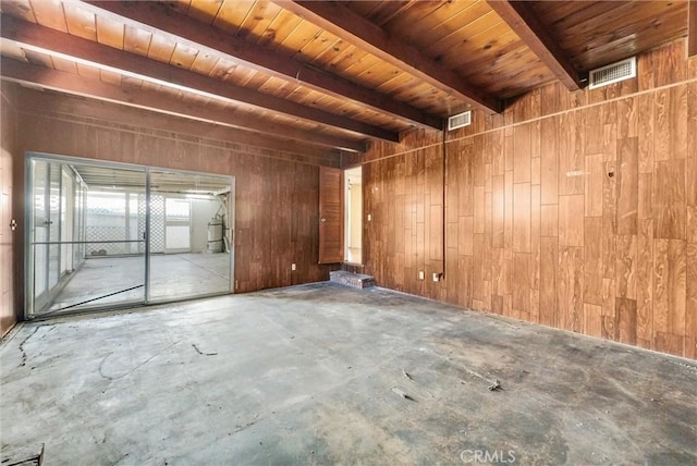 empty room featuring wooden ceiling, wood walls, beamed ceiling, and concrete flooring