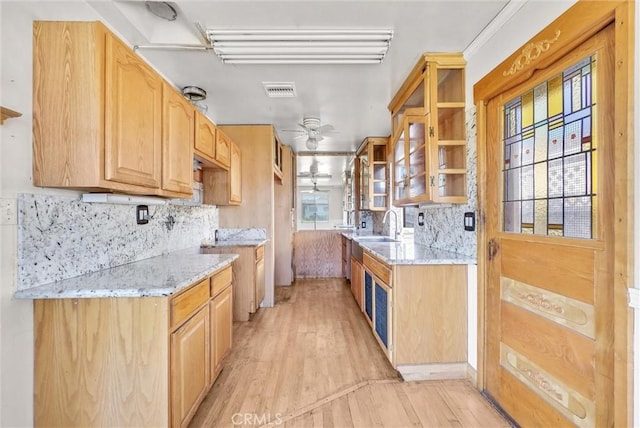 kitchen featuring ceiling fan, tasteful backsplash, and light stone countertops