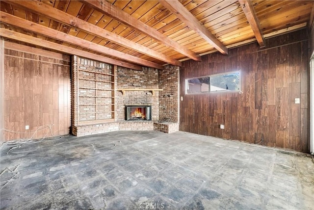 unfurnished living room with beam ceiling, wood ceiling, a brick fireplace, and wood walls