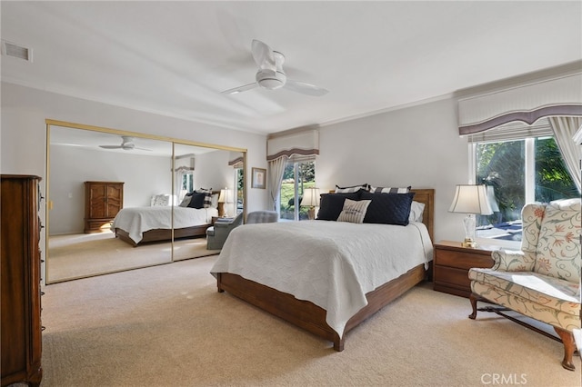 bedroom with ceiling fan, a closet, light carpet, and multiple windows