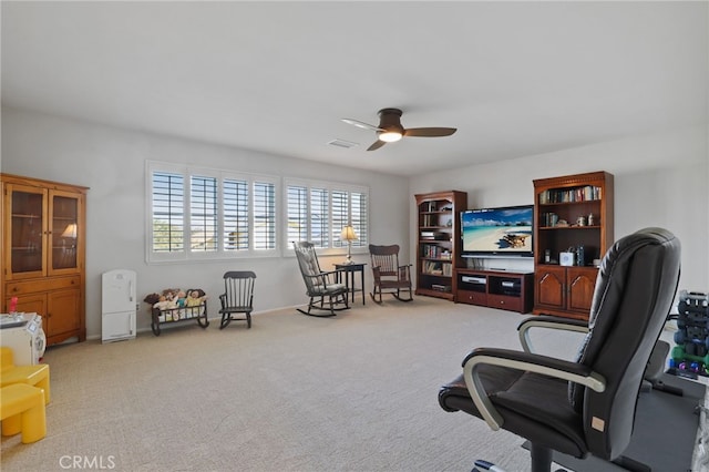 sitting room with ceiling fan and light colored carpet