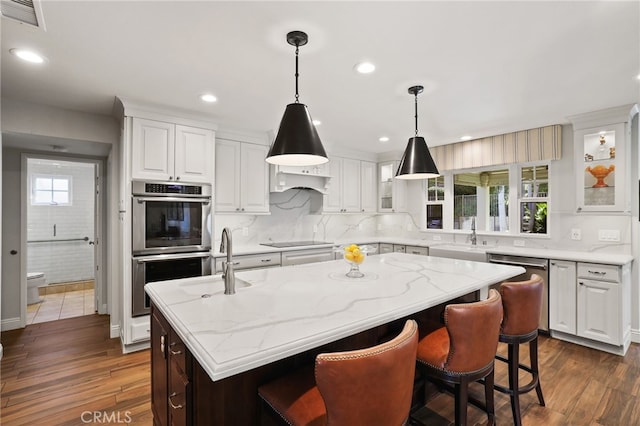 kitchen with appliances with stainless steel finishes, a kitchen island, white cabinetry, sink, and dark hardwood / wood-style floors