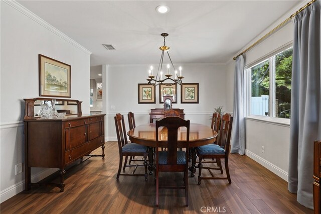 dining room featuring dark wood-type flooring, an inviting chandelier, and ornamental molding