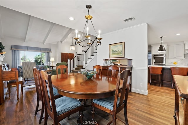 dining space with lofted ceiling with beams, a chandelier, and light wood-type flooring