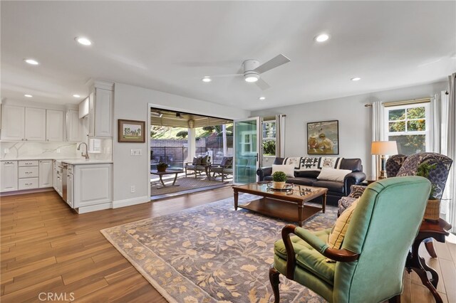 living room with ceiling fan, light hardwood / wood-style flooring, and sink