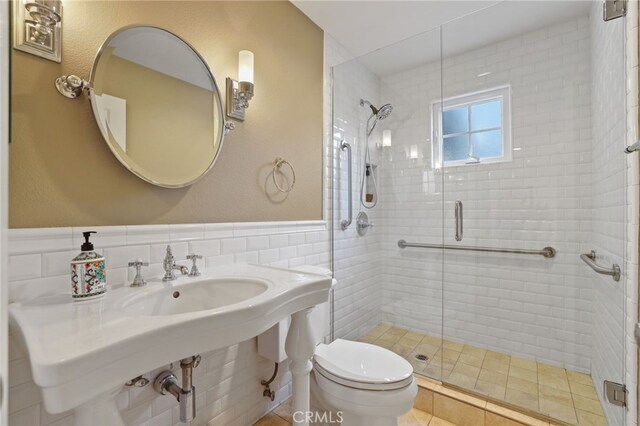 bathroom with toilet, tile walls, and a shower with shower door