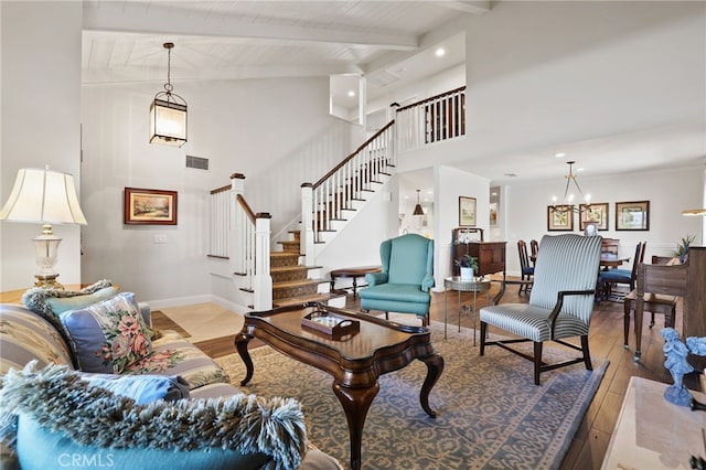 living room featuring beam ceiling, light hardwood / wood-style flooring, an inviting chandelier, and wooden ceiling