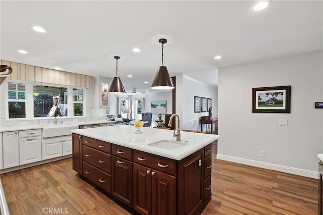 kitchen with dark hardwood / wood-style floors, pendant lighting, a center island with sink, and sink