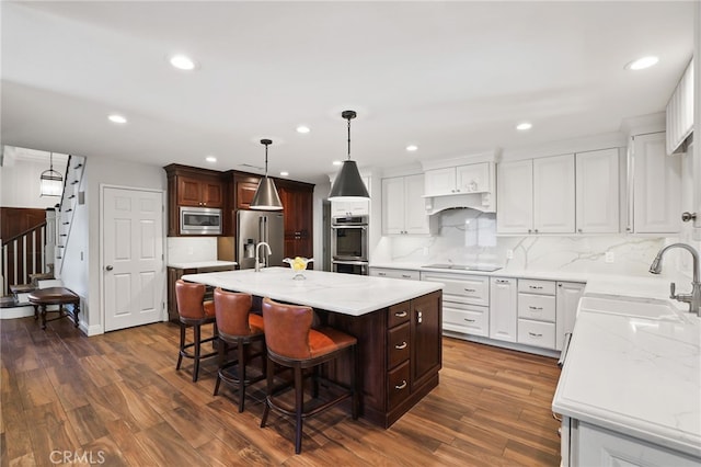 kitchen with dark hardwood / wood-style floors, stainless steel appliances, a center island with sink, and sink