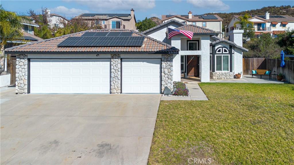 view of front of home with solar panels, a front lawn, and a garage