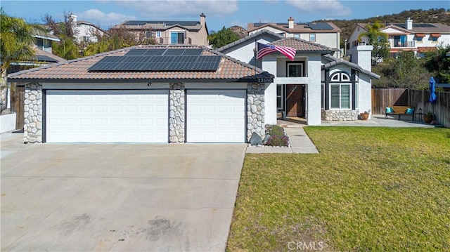 view of front of home with solar panels, a front lawn, and a garage