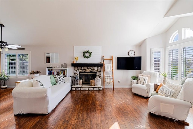 living room with dark hardwood / wood-style floors, ceiling fan, a healthy amount of sunlight, and a stone fireplace