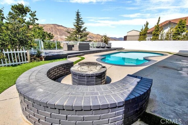 view of swimming pool featuring an outdoor living space with a fire pit, a mountain view, and a patio area