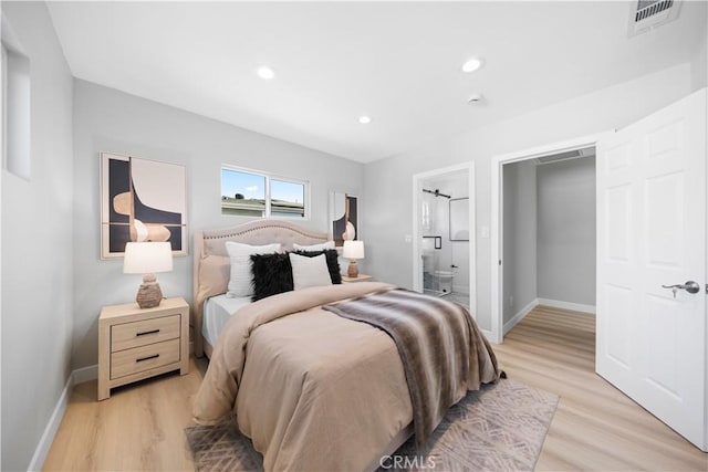 bedroom featuring connected bathroom and light hardwood / wood-style floors