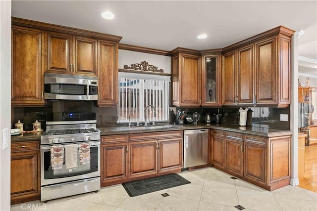 kitchen with light tile patterned floors, decorative backsplash, crown molding, appliances with stainless steel finishes, and sink