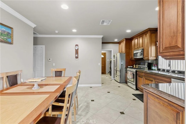 kitchen featuring sink, ornamental molding, light tile patterned floors, and appliances with stainless steel finishes