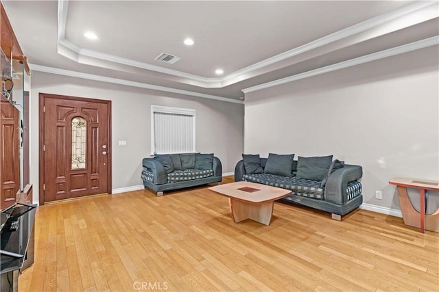 living room with ornamental molding, light hardwood / wood-style flooring, and a raised ceiling