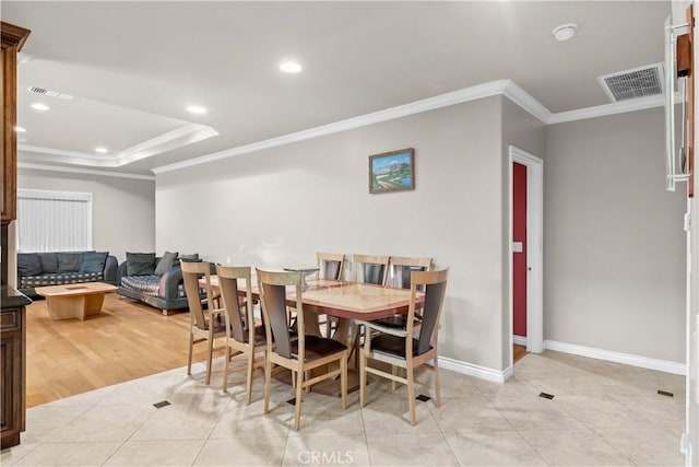 dining space with crown molding, a raised ceiling, and light tile patterned flooring