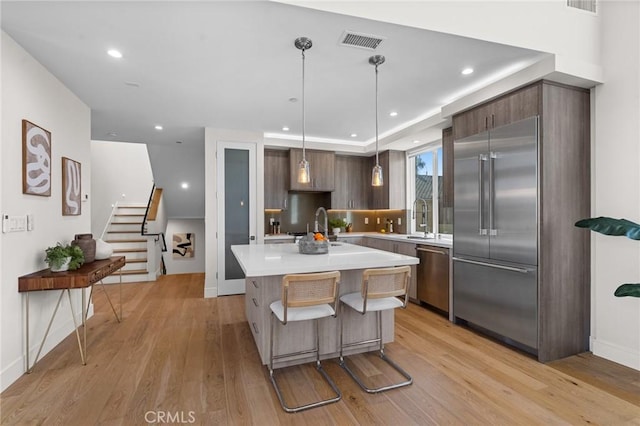 kitchen with appliances with stainless steel finishes, light hardwood / wood-style floors, a center island, sink, and dark brown cabinets