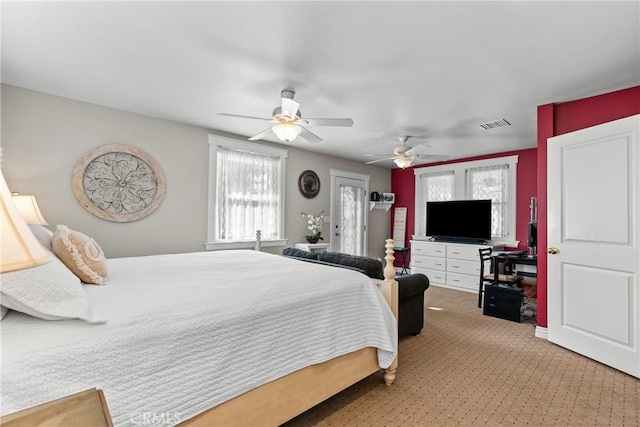 bedroom featuring a ceiling fan, visible vents, and light carpet