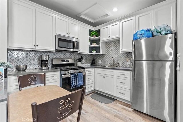 kitchen featuring dark countertops, appliances with stainless steel finishes, white cabinets, and a sink