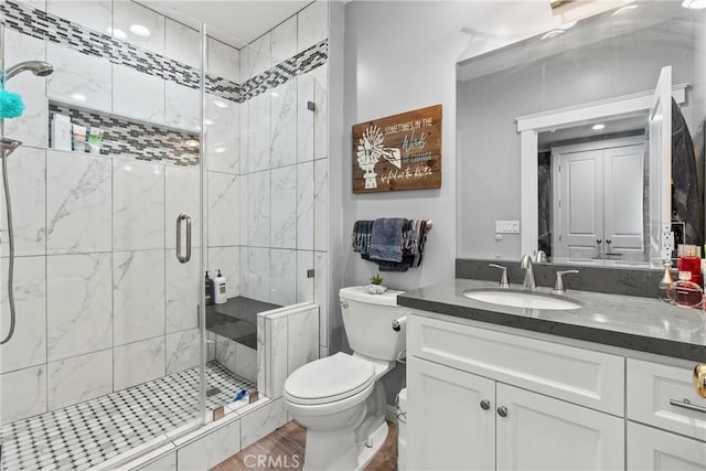 bathroom with toilet, a shower stall, and vanity