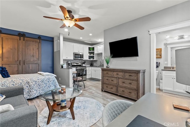 bedroom featuring recessed lighting, ensuite bath, light wood-style flooring, and a barn door