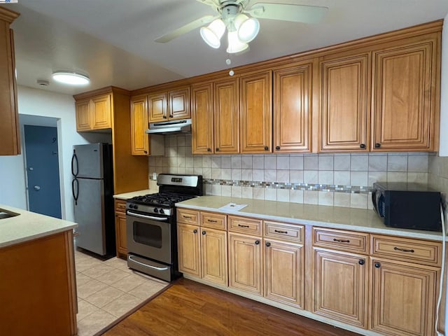 kitchen featuring ceiling fan, light hardwood / wood-style floors, backsplash, and stainless steel appliances