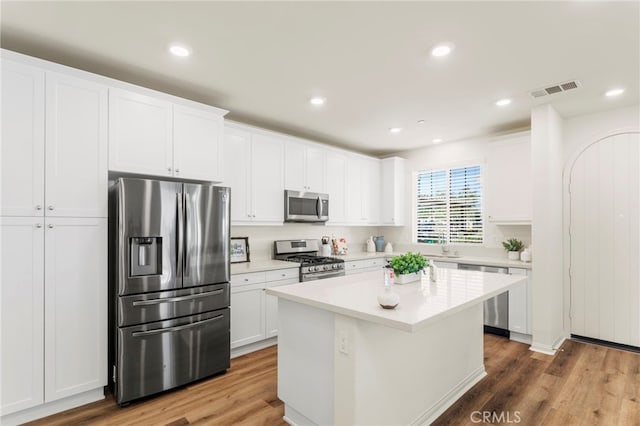 kitchen featuring white cabinets, stainless steel appliances, a kitchen island, and hardwood / wood-style flooring