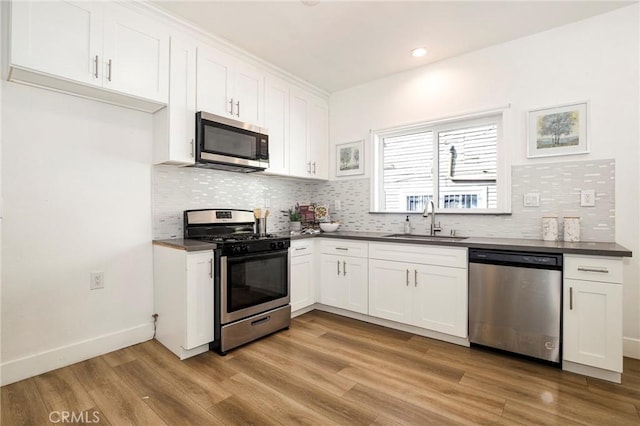 kitchen featuring appliances with stainless steel finishes, light hardwood / wood-style floors, white cabinets, and sink