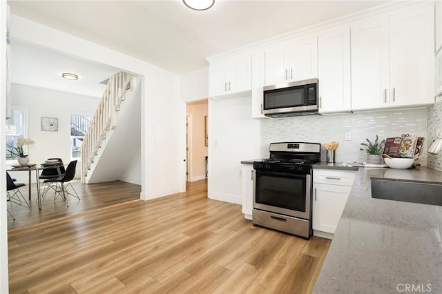 kitchen featuring light stone countertops, stainless steel appliances, decorative backsplash, white cabinets, and sink