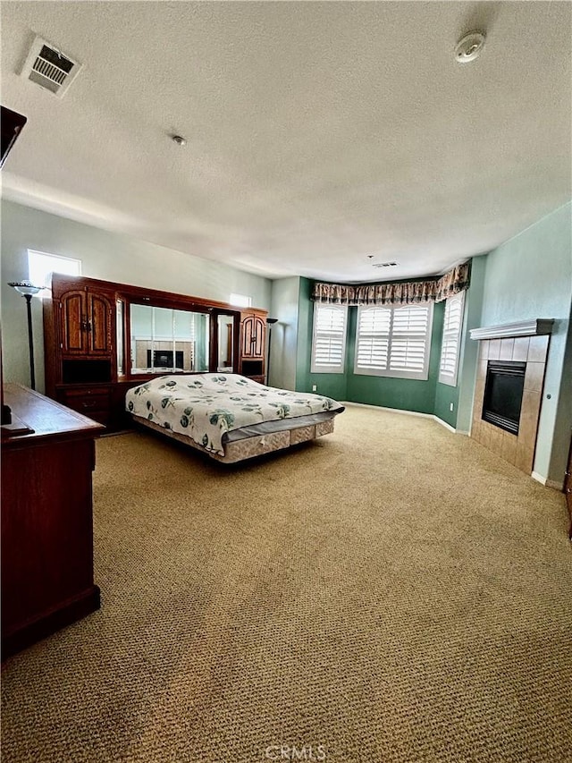 unfurnished bedroom featuring a tiled fireplace, a textured ceiling, and carpet flooring