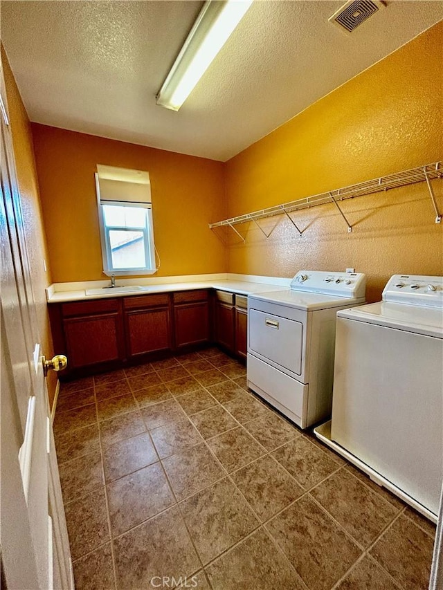 laundry room with separate washer and dryer, cabinets, sink, and a textured ceiling