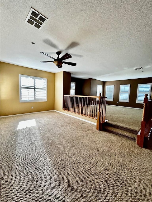 carpeted spare room featuring a textured ceiling and ceiling fan