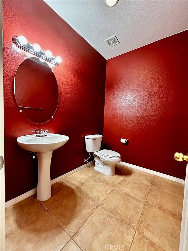 bathroom featuring a textured ceiling, tile patterned flooring, sink, and toilet