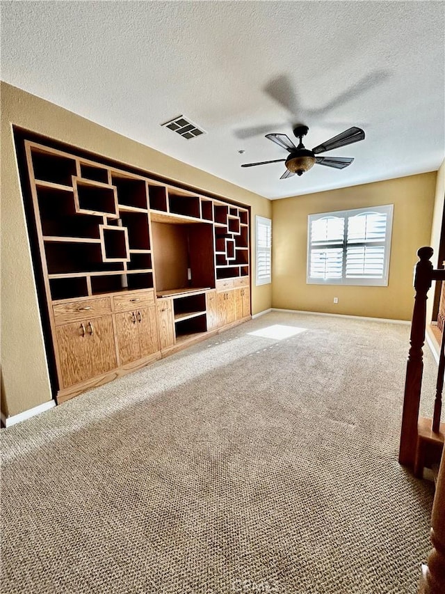 unfurnished living room with ceiling fan, a textured ceiling, and carpet flooring