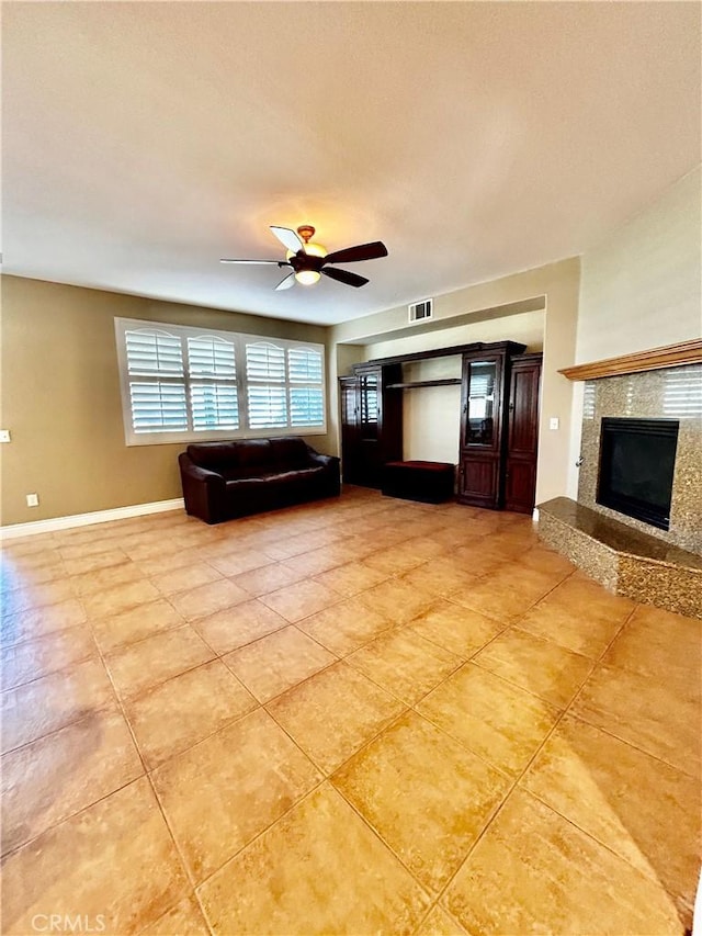 unfurnished living room with a tiled fireplace, ceiling fan, and light tile patterned floors