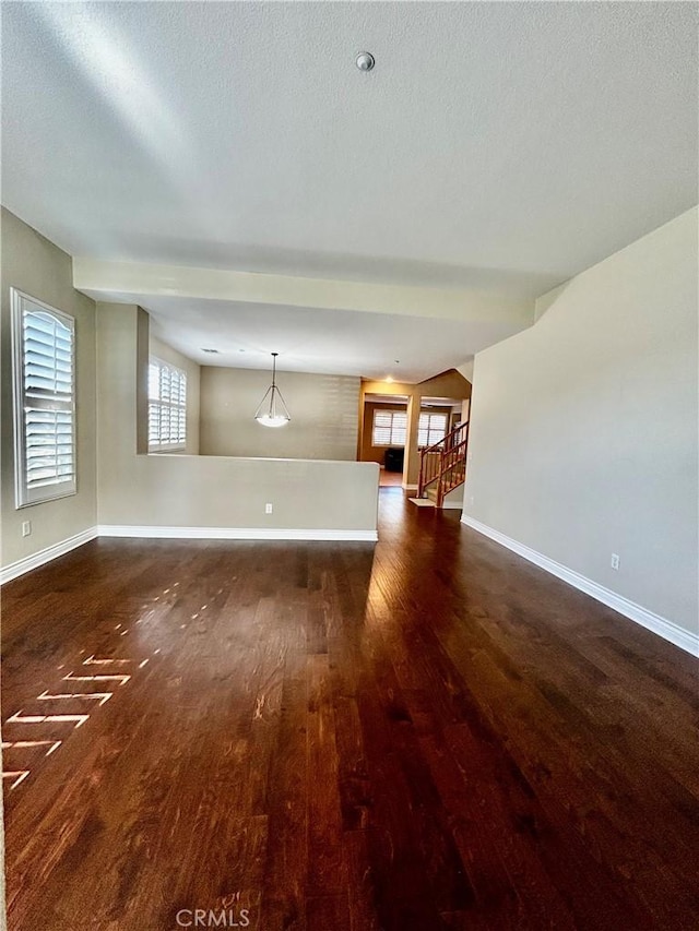 unfurnished living room with a textured ceiling, a wealth of natural light, and dark hardwood / wood-style floors