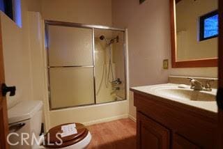 full bathroom featuring toilet, vanity, and shower / bath combination with glass door