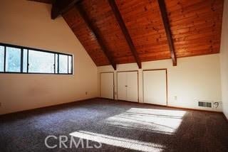 additional living space featuring carpet floors, lofted ceiling with beams, and wood ceiling