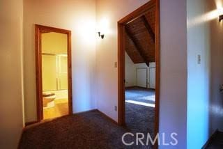 hallway featuring dark carpet, lofted ceiling with beams, and wood ceiling