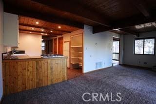 kitchen with wooden ceiling, beamed ceiling, and dark colored carpet