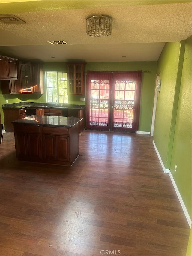 kitchen featuring a textured ceiling, a center island, sink, and dark hardwood / wood-style floors