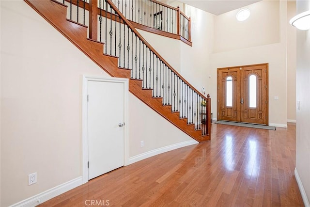 foyer with wood-type flooring and a towering ceiling