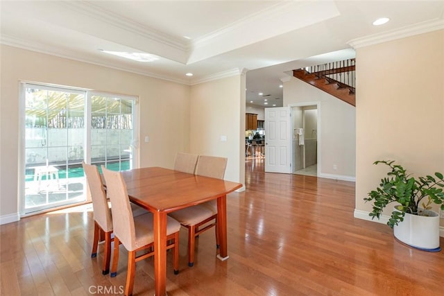 dining room with hardwood / wood-style flooring, ornamental molding, and a tray ceiling