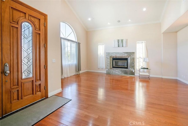 foyer entrance with a premium fireplace, ornamental molding, and light wood-type flooring