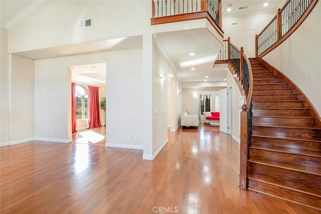 entrance foyer with a high ceiling, light wood-type flooring, and crown molding