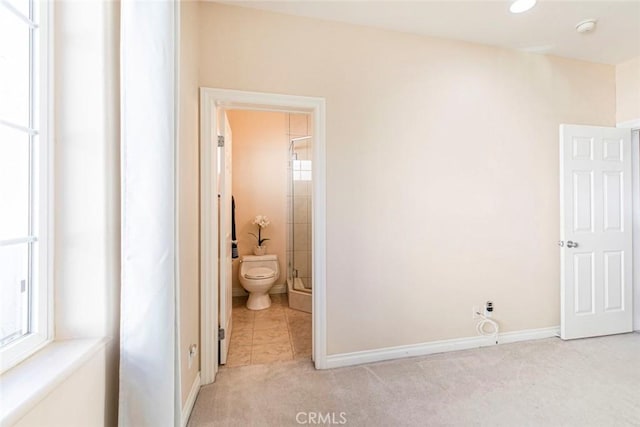 bedroom featuring light carpet and ensuite bath