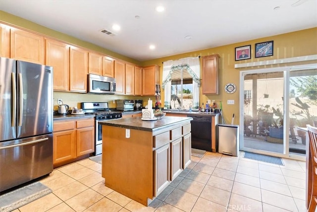 kitchen with appliances with stainless steel finishes, light tile patterned flooring, and a center island